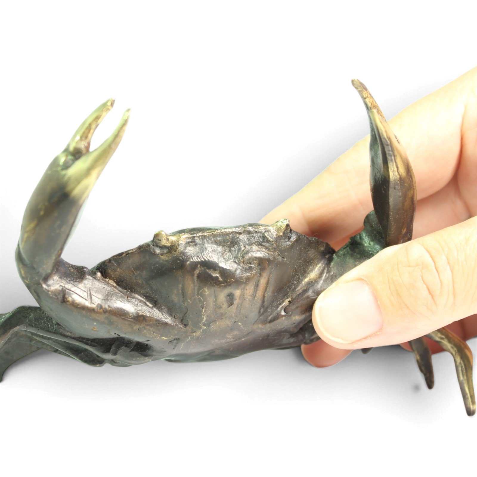Hand holding the brass crab figurine to show scale and claw detail