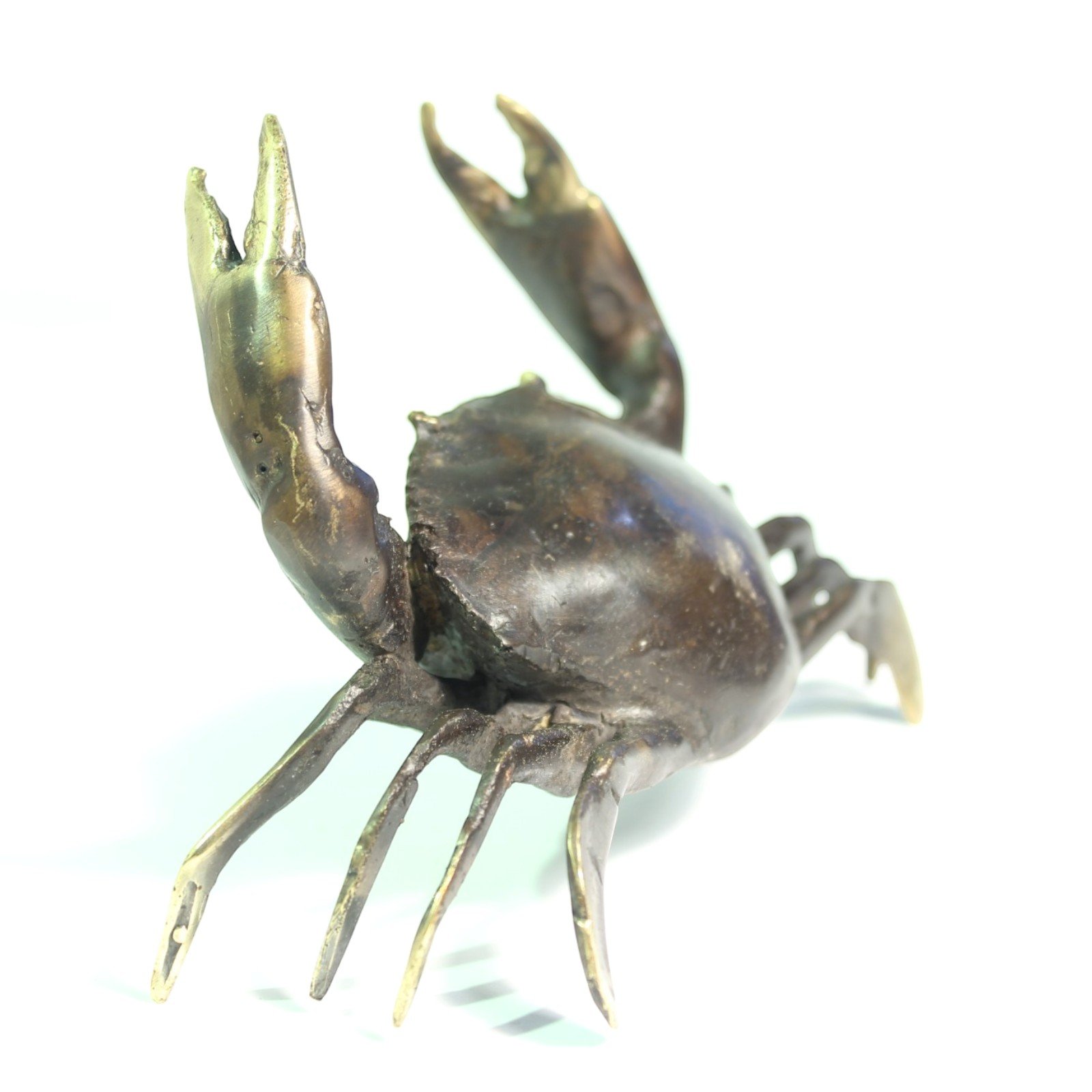 Close angled view of brass crab showing legs, shell texture, and raised claws