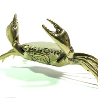 Close-up side view of gold-tone brass crab figurine with claws raised