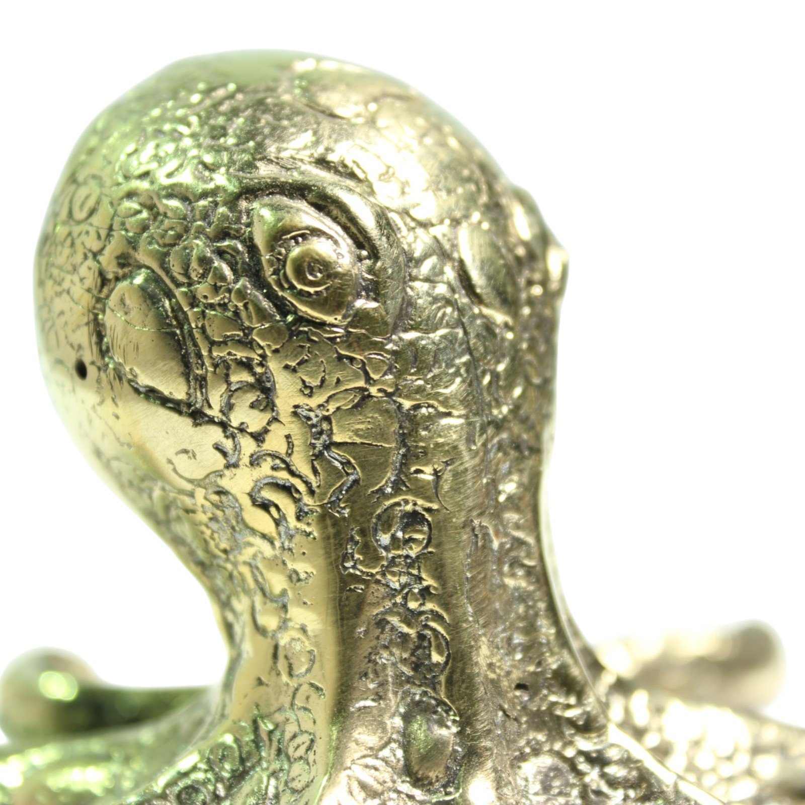 Close-up of a hand lifting the brass octopus by its head, showing solid cast weight