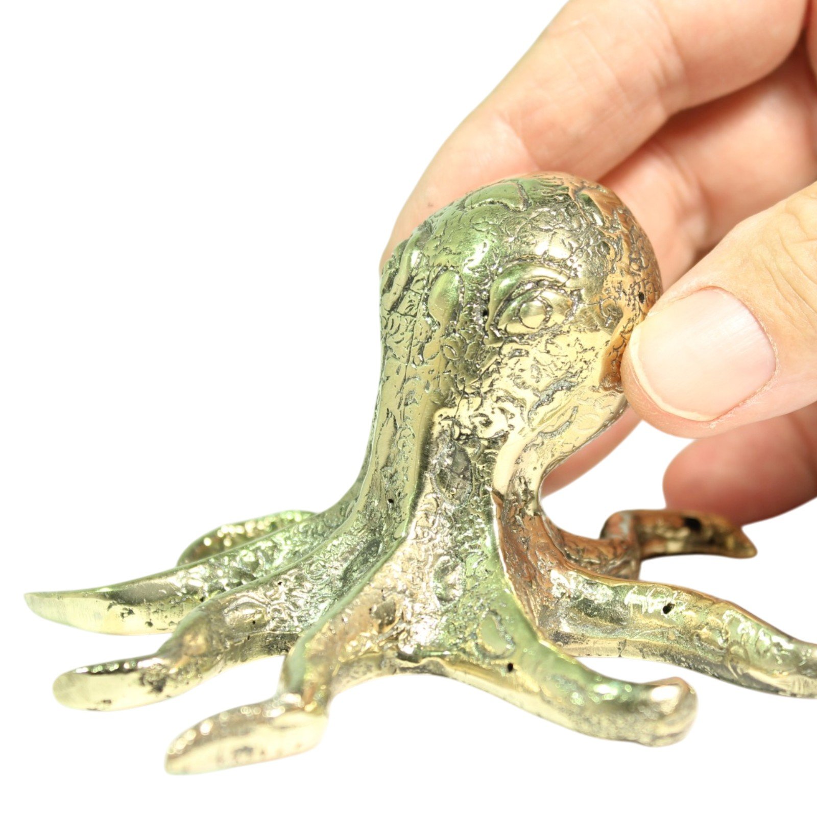 Staged photo of the brass octopus figurine on a desk with notebook and pen for size reference