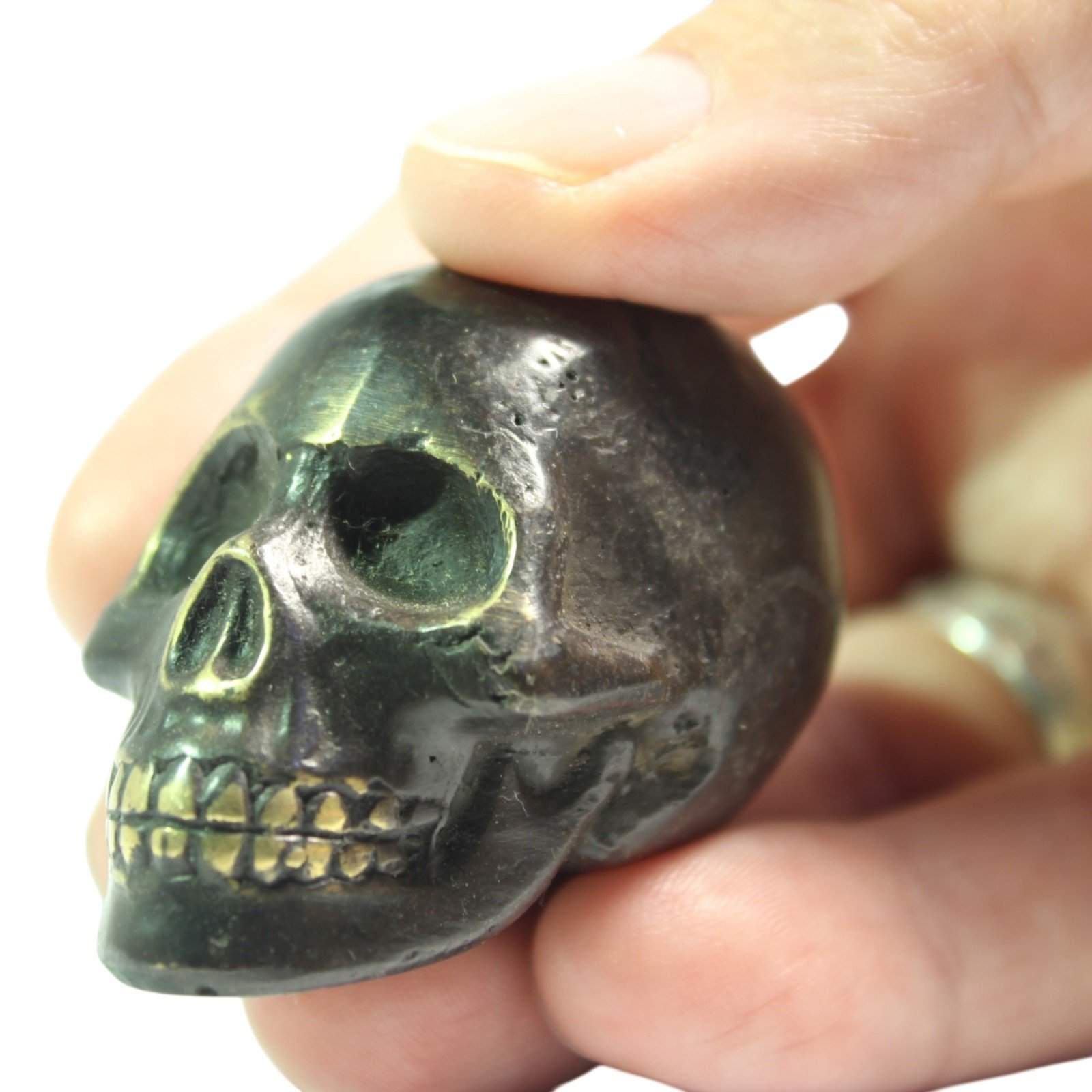 Hand holding the brass skull figurine to show its compact scale