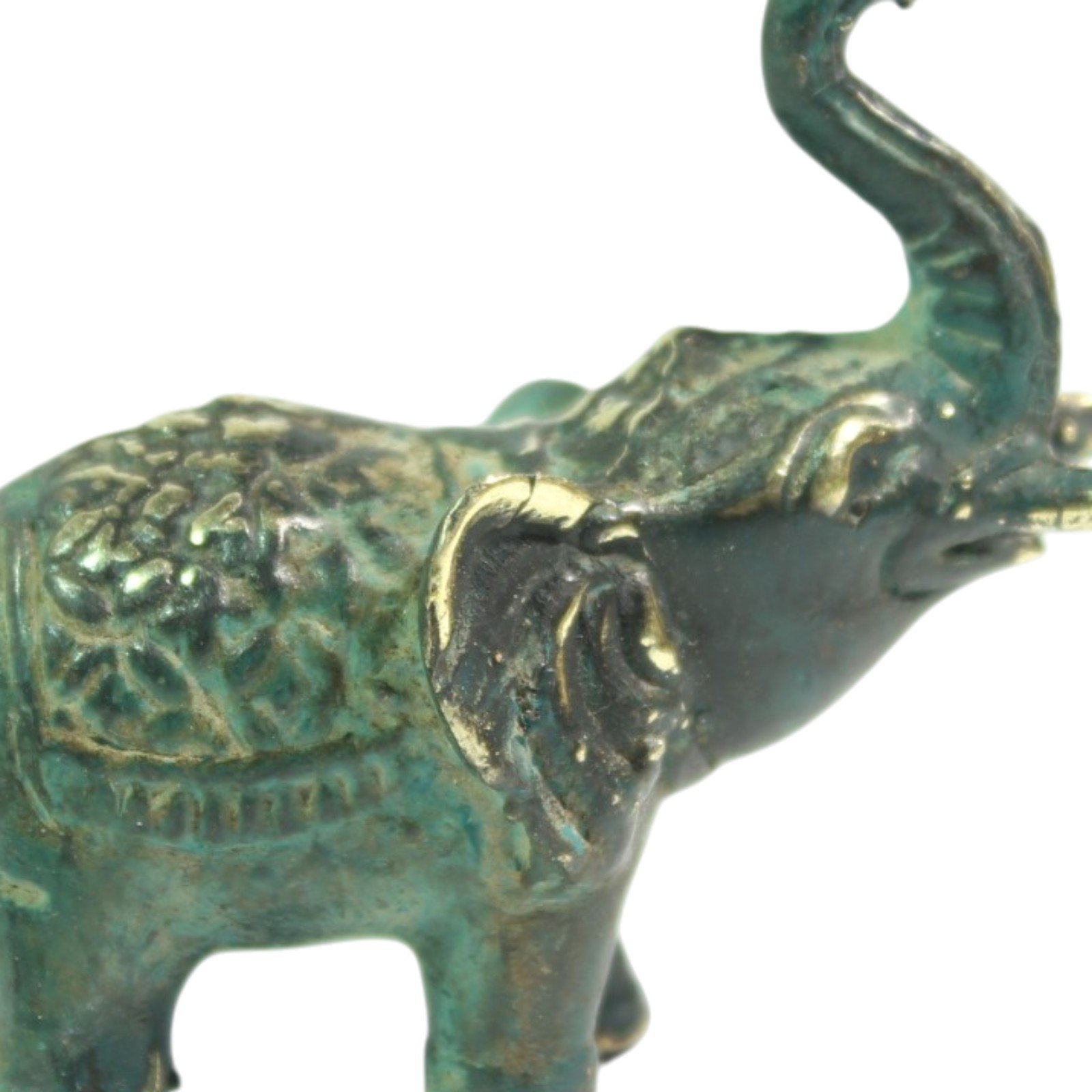 Close-up of elephant's head and ear showing hand-carved texture and brass highlights against patina