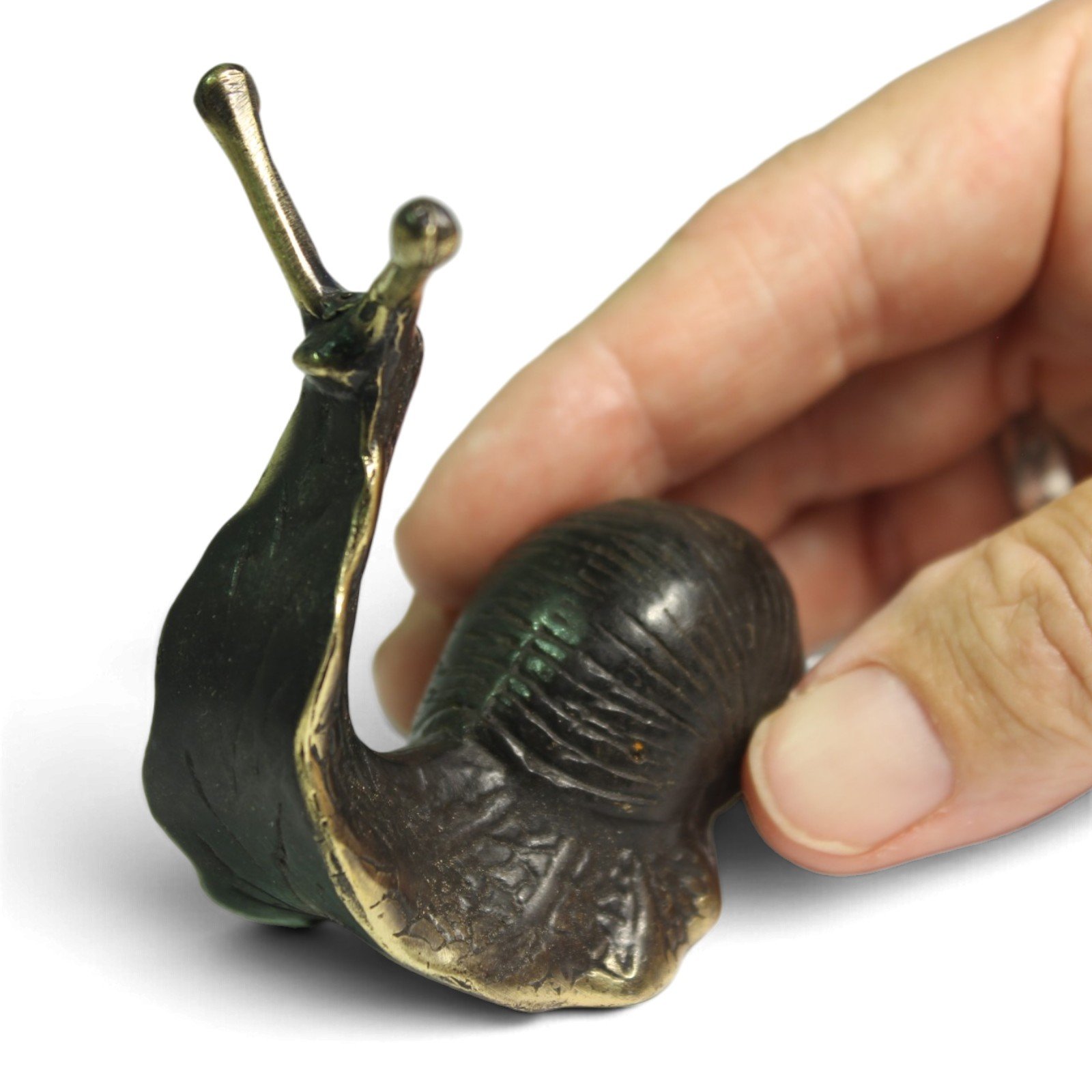 Close-up of hand touching brass snail's shell, showing oxidized patina and gold accents