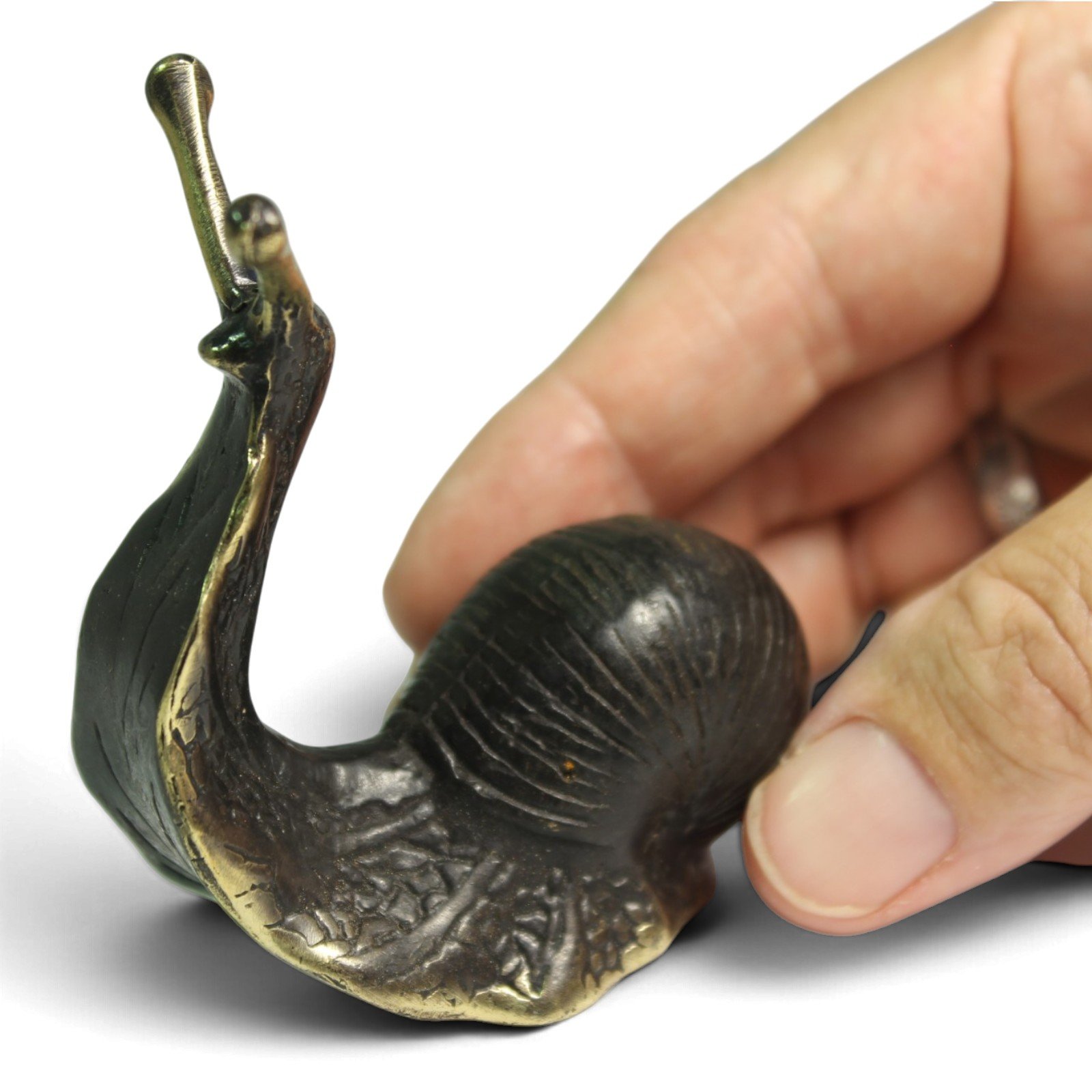 Close-up of hand holding brass snail figurine to show scale and finish detail