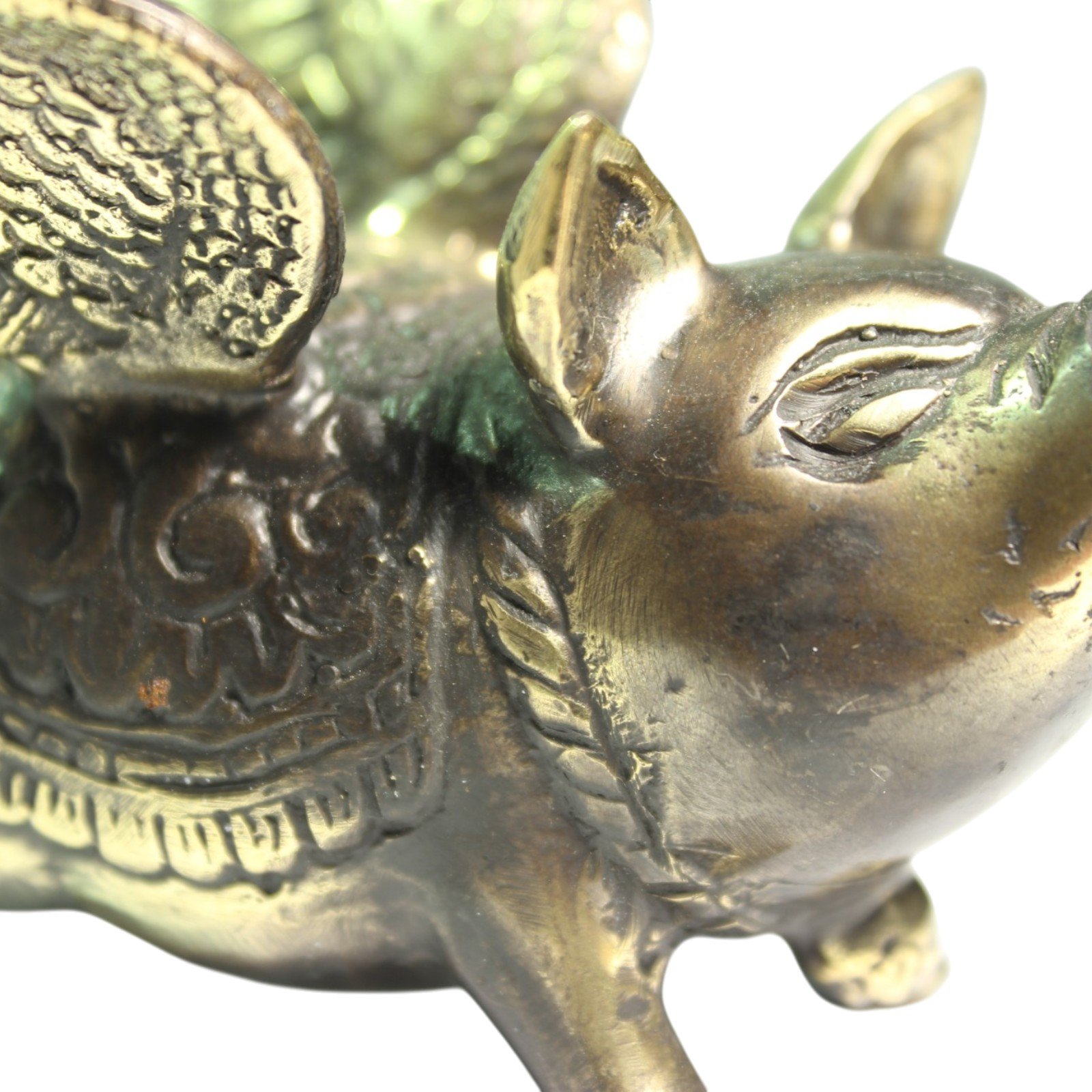Close side View of hand-cast brass pig showing carved wing feathers and back pattern