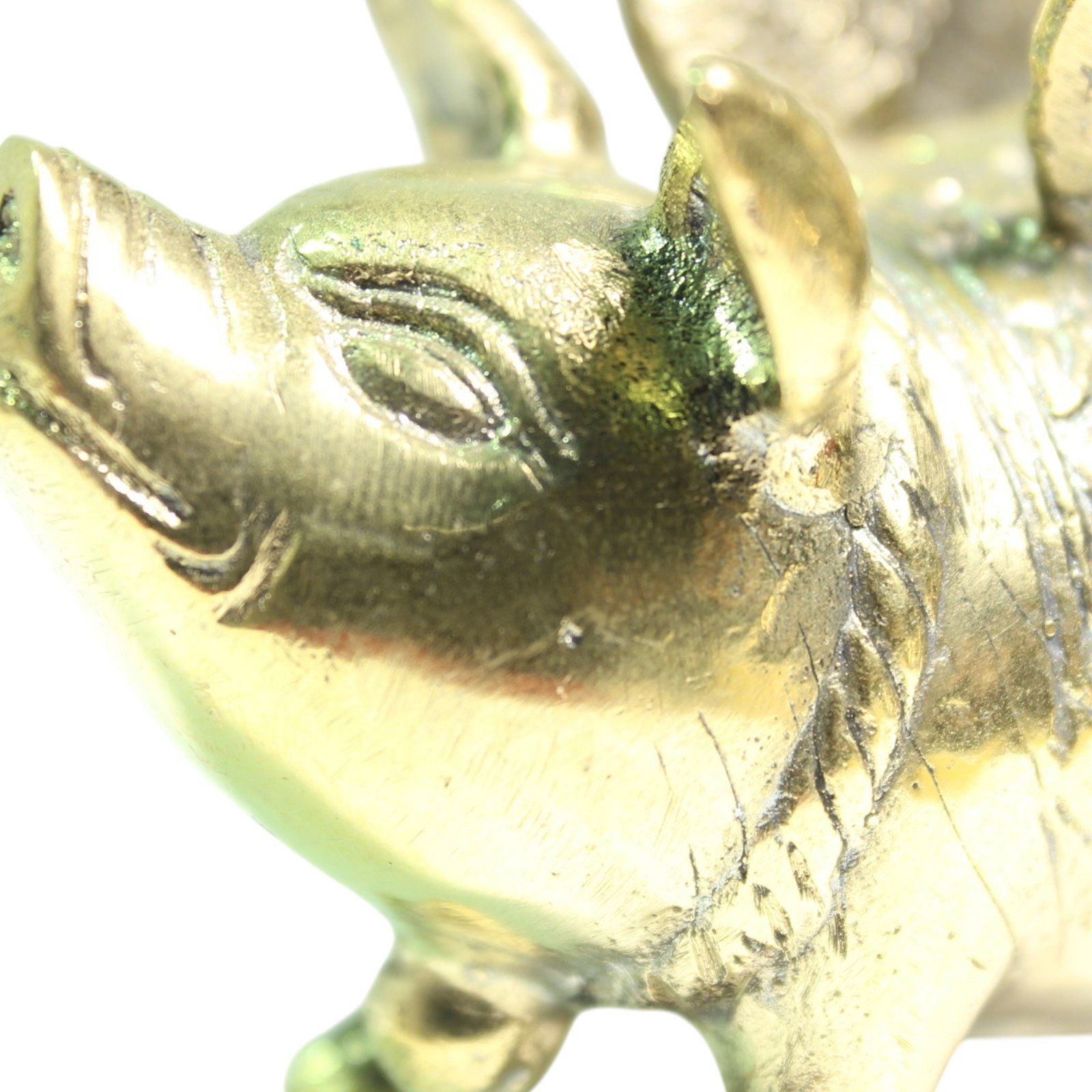 Brass winged pig figurine viewed from the side, showing detailed feathered wings and engraved saddle pattern