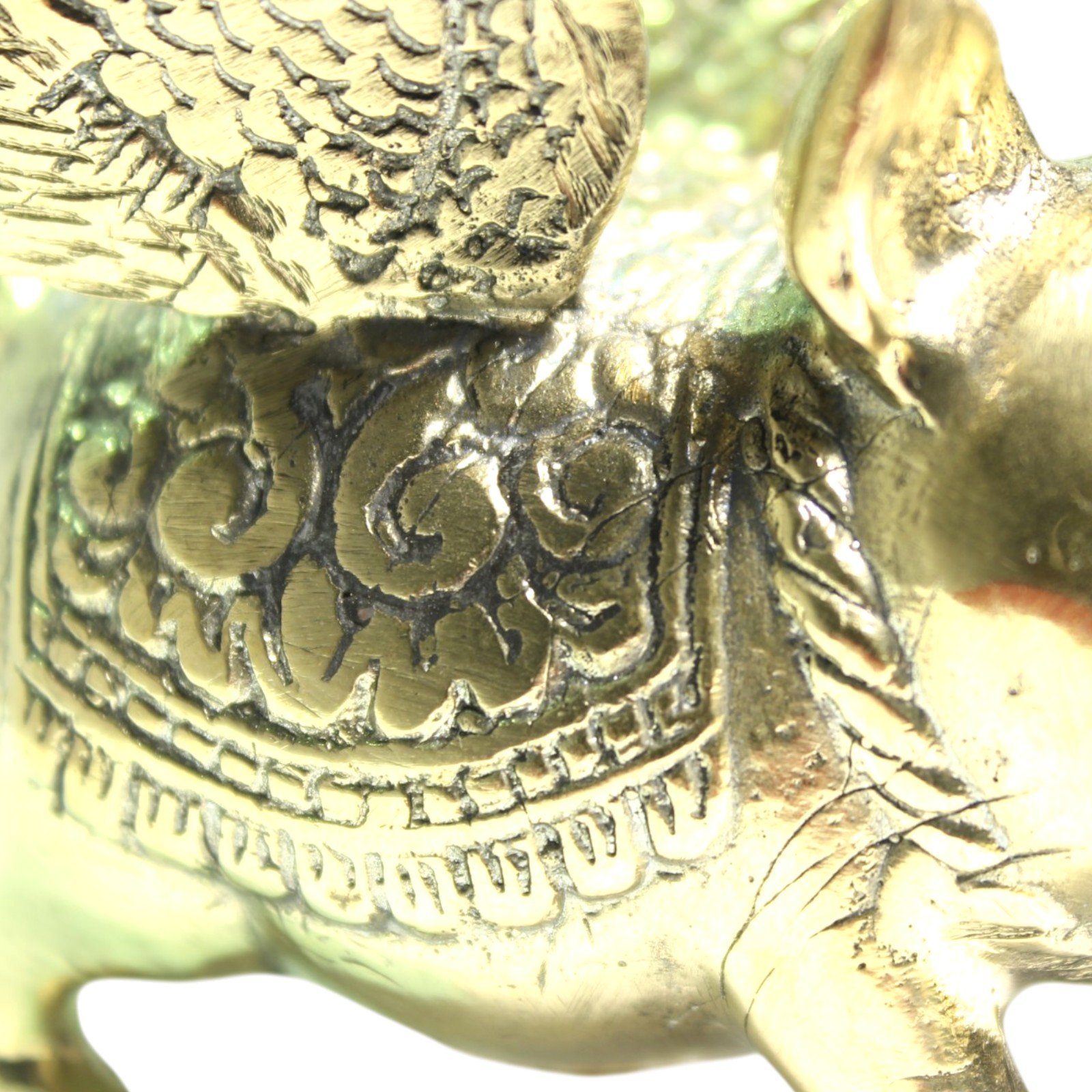 Brass winged pig figurine viewed from the side, showing detailed feathered wings and engraved saddle pattern