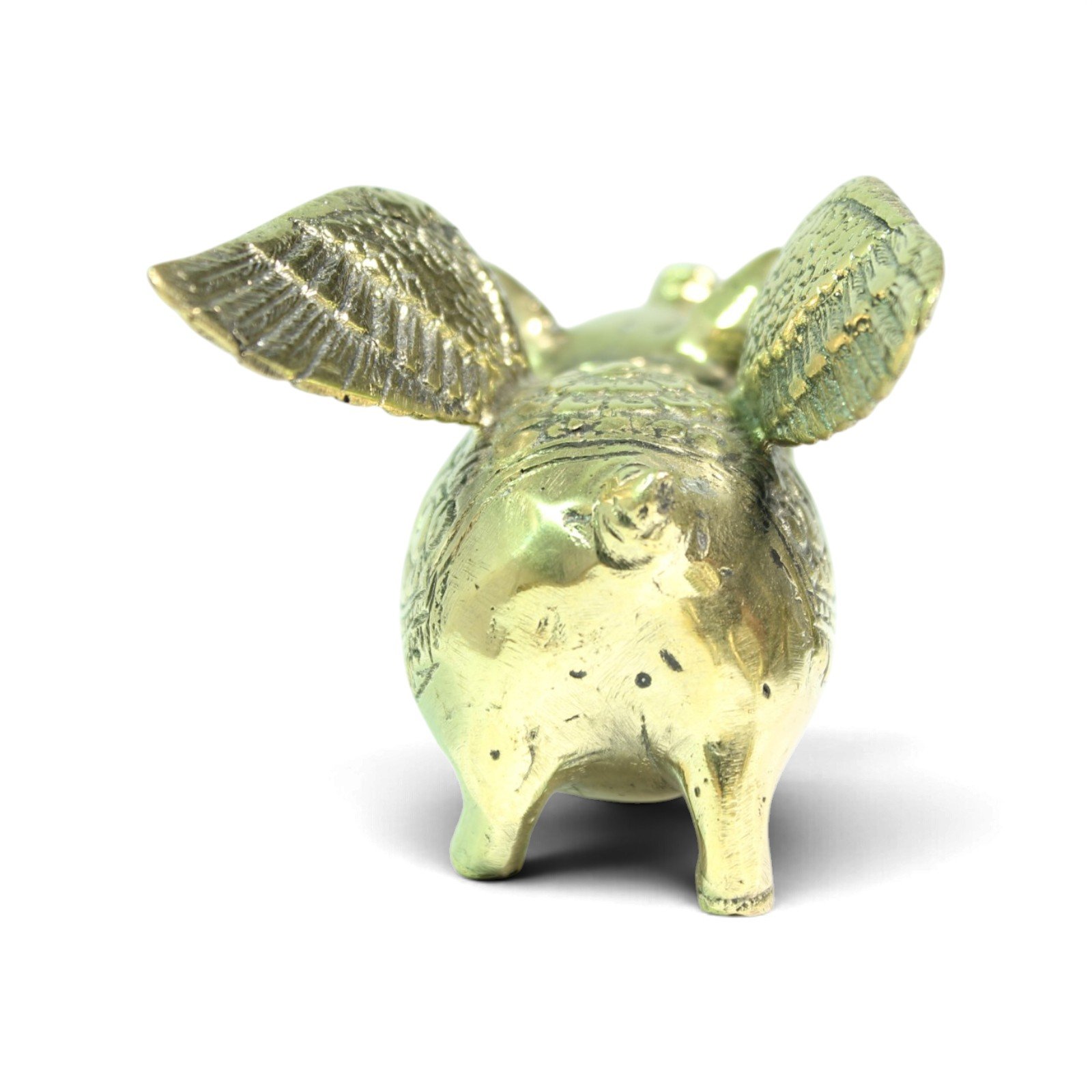 Back view of brass pig figurine facing away, showing tail, hind legs, and wing undersides
