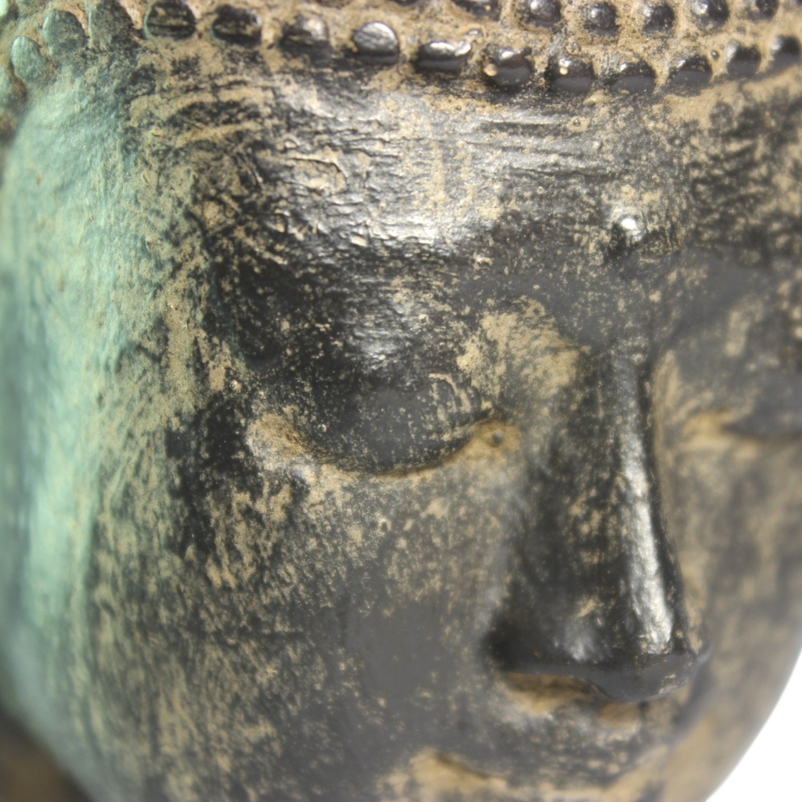 Close-up of the Buddha's face showing hand-applied antiquing and texture