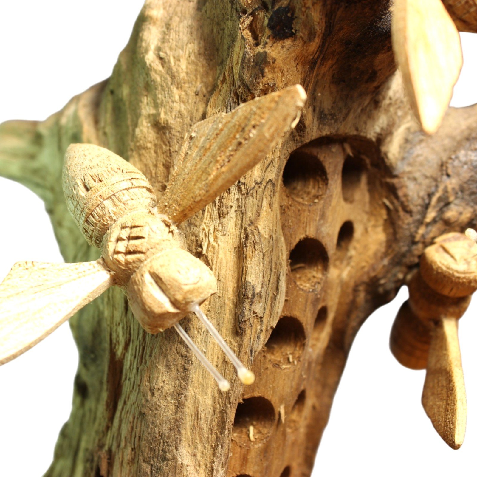 Close-up of a single carved bee with textured wings resting on the wood grain