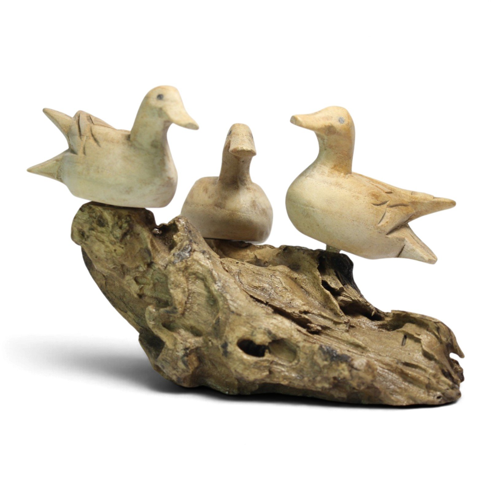 Side view of three carved wooden ducks lined up on their natural wood perch