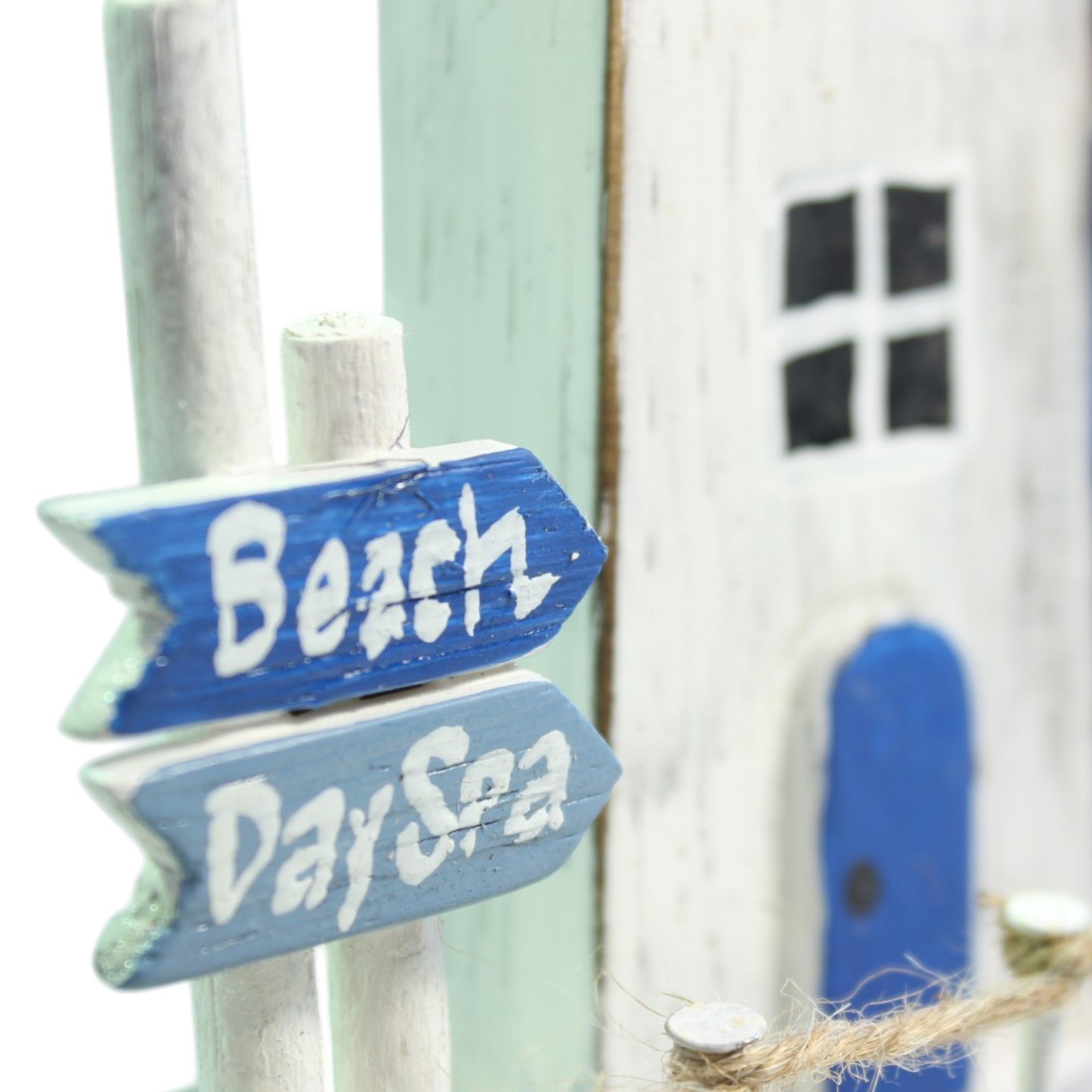 Close-up of the hand-lettered 'Beach' and 'Day Spa' wooden signpost