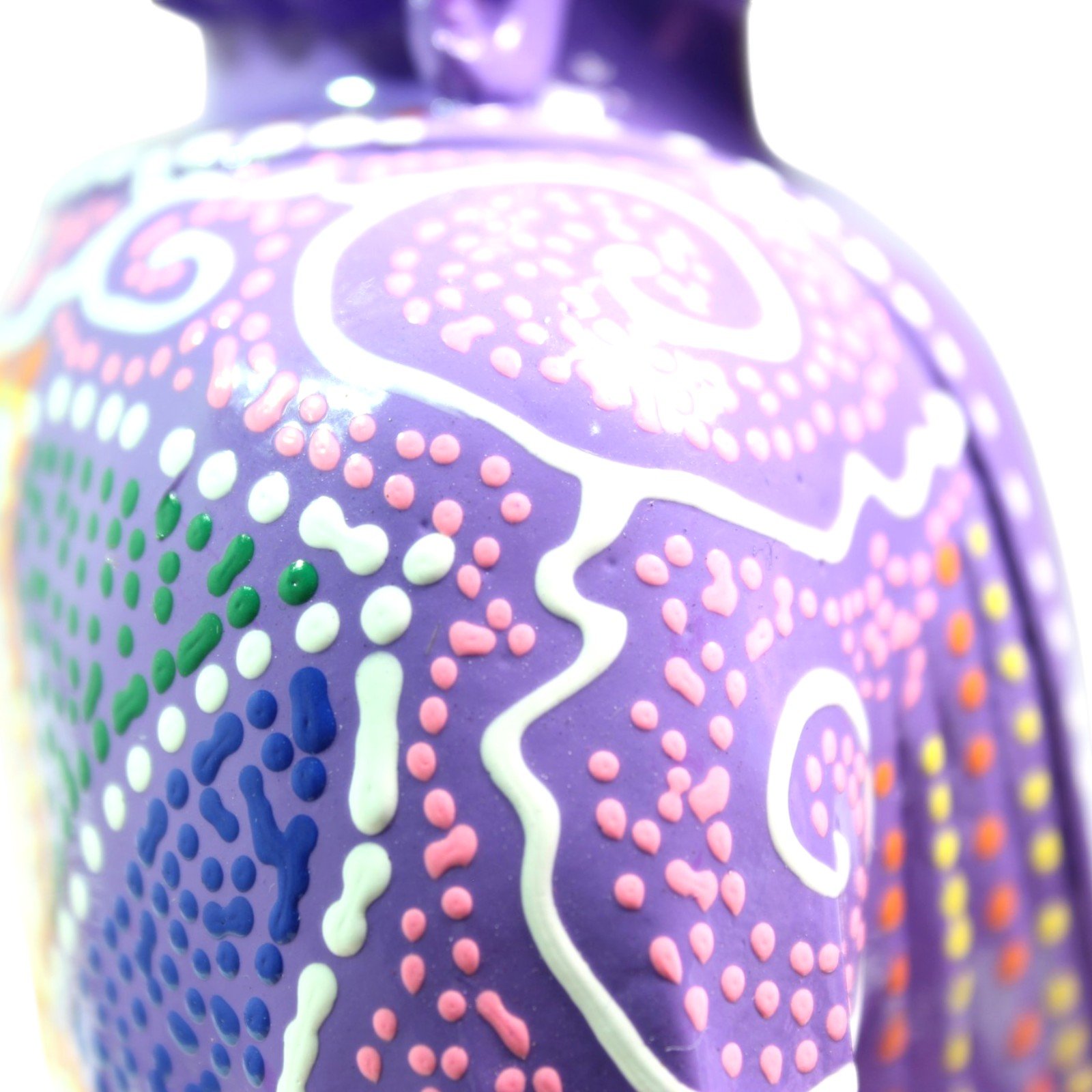 Macro shot of the hand-painted dot pattern on the Buddha's robe in pink, white, green, and blue
