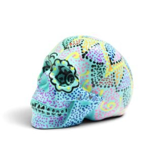 Turquoise resin skull figurine with colorful dot-art painting, three-quarter angle view