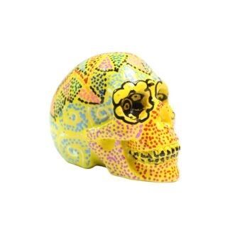 Three-quarter angle view of yellow skull figurine with colorful painted patterns