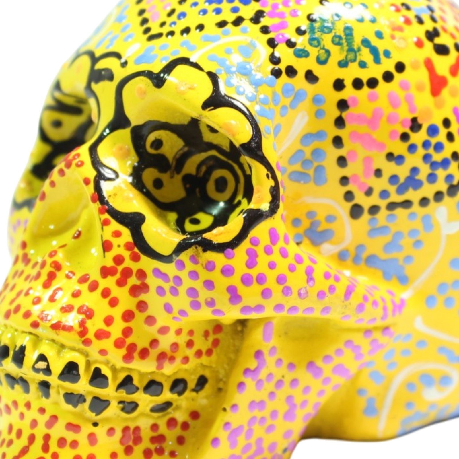 Close-up of hand-painted eye socket detail on yellow resin skull with dotted patterns