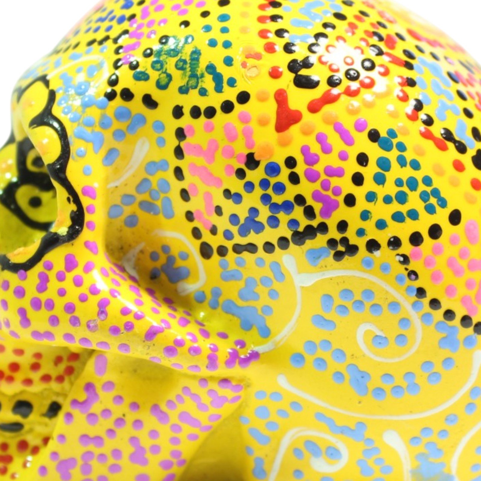 Close-up of colorful dotted paint pattern on top of the yellow skull