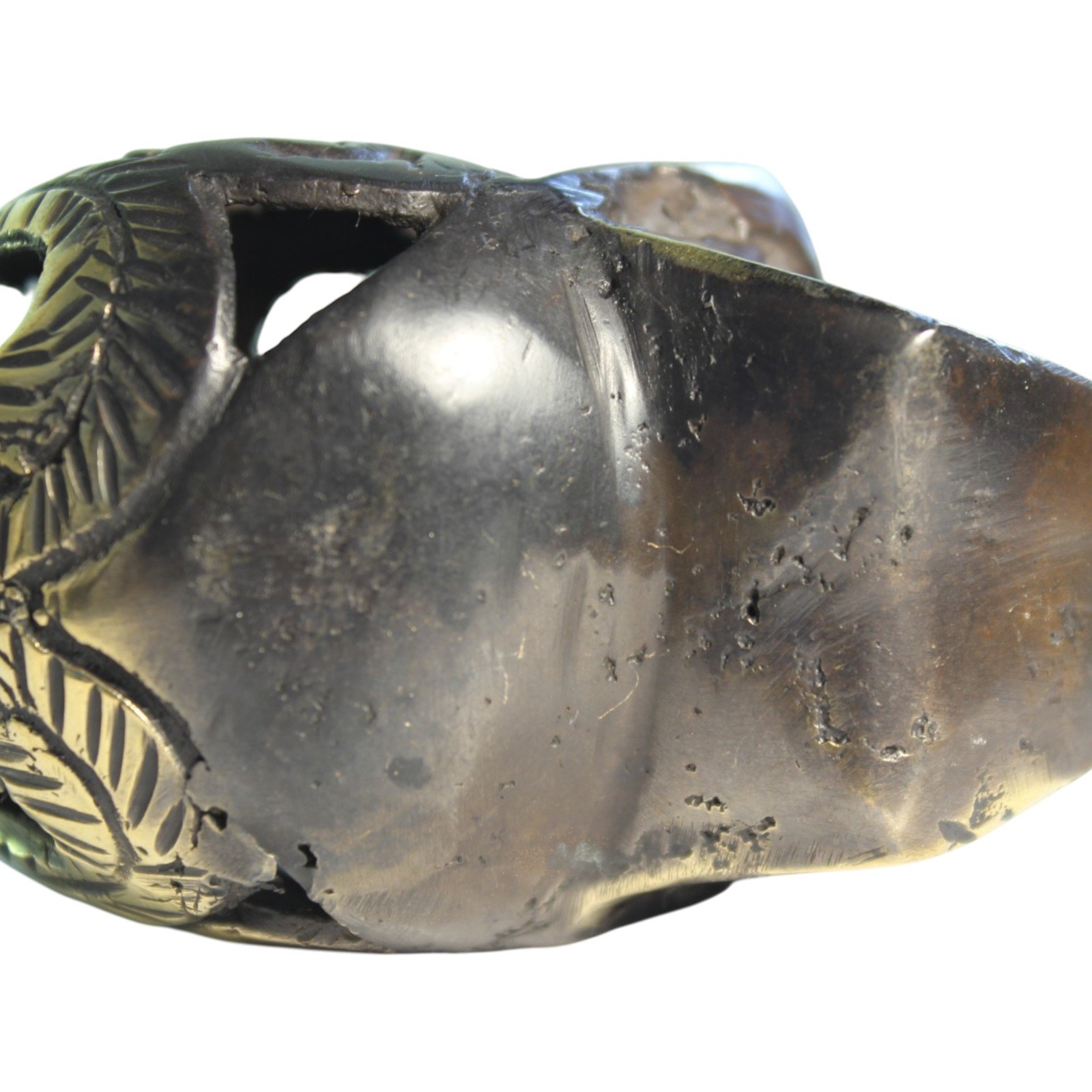 Handvara view of the brass skull figurine showing symmetrical carving and aged finish