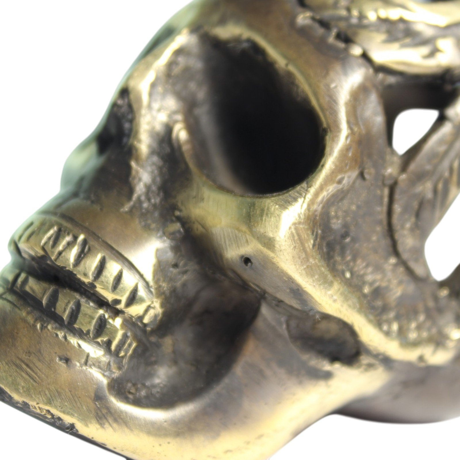 Handvara view of the brass skull figurine showing symmetrical carving and aged finish