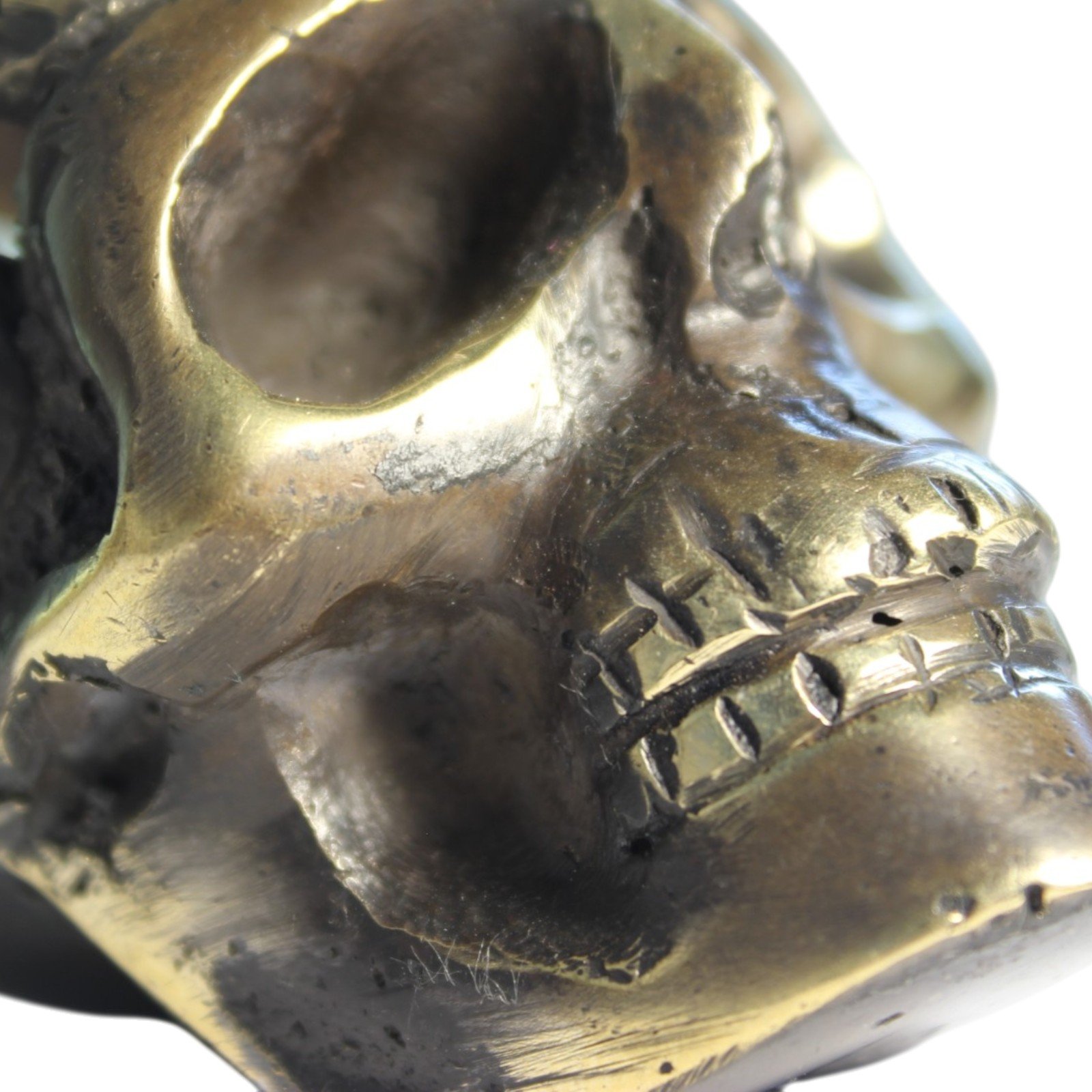 Handvara view of the brass skull figurine showing symmetrical carving and aged finish