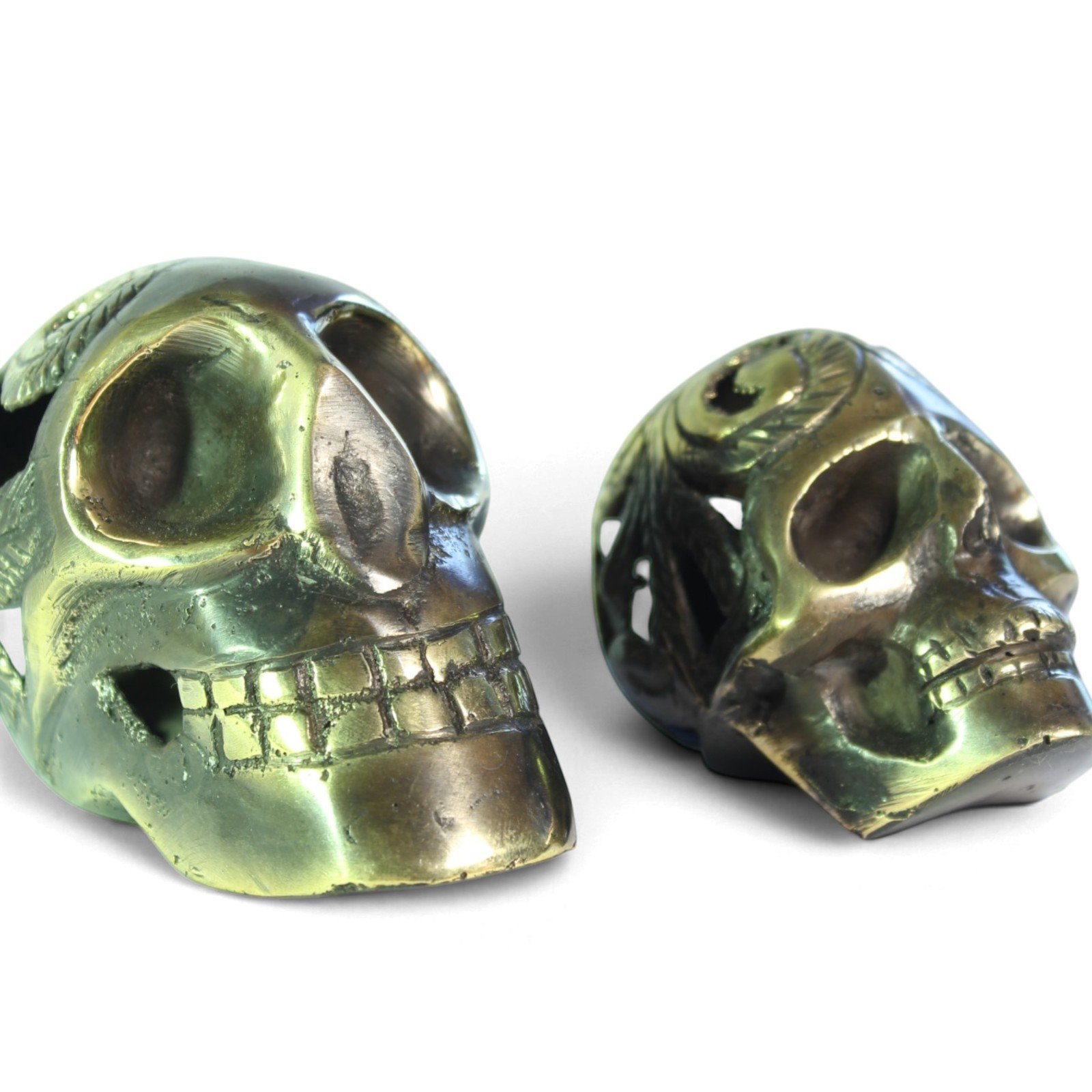 Close-up of two brass skulls showing carved teeth, eye sockets, and casting texture