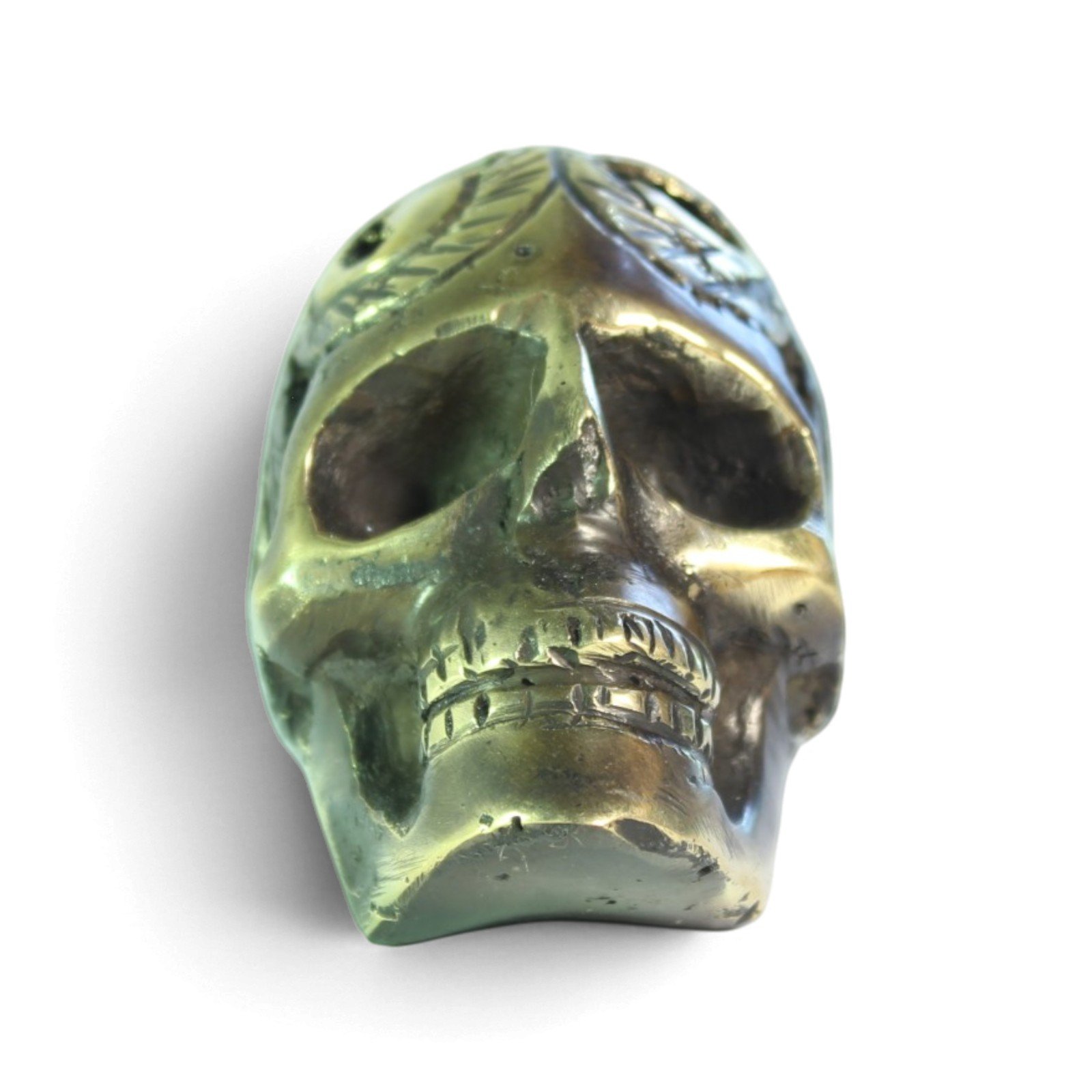 Front-facing view of the brass skull figurine showing symmetrical carving and aged finish