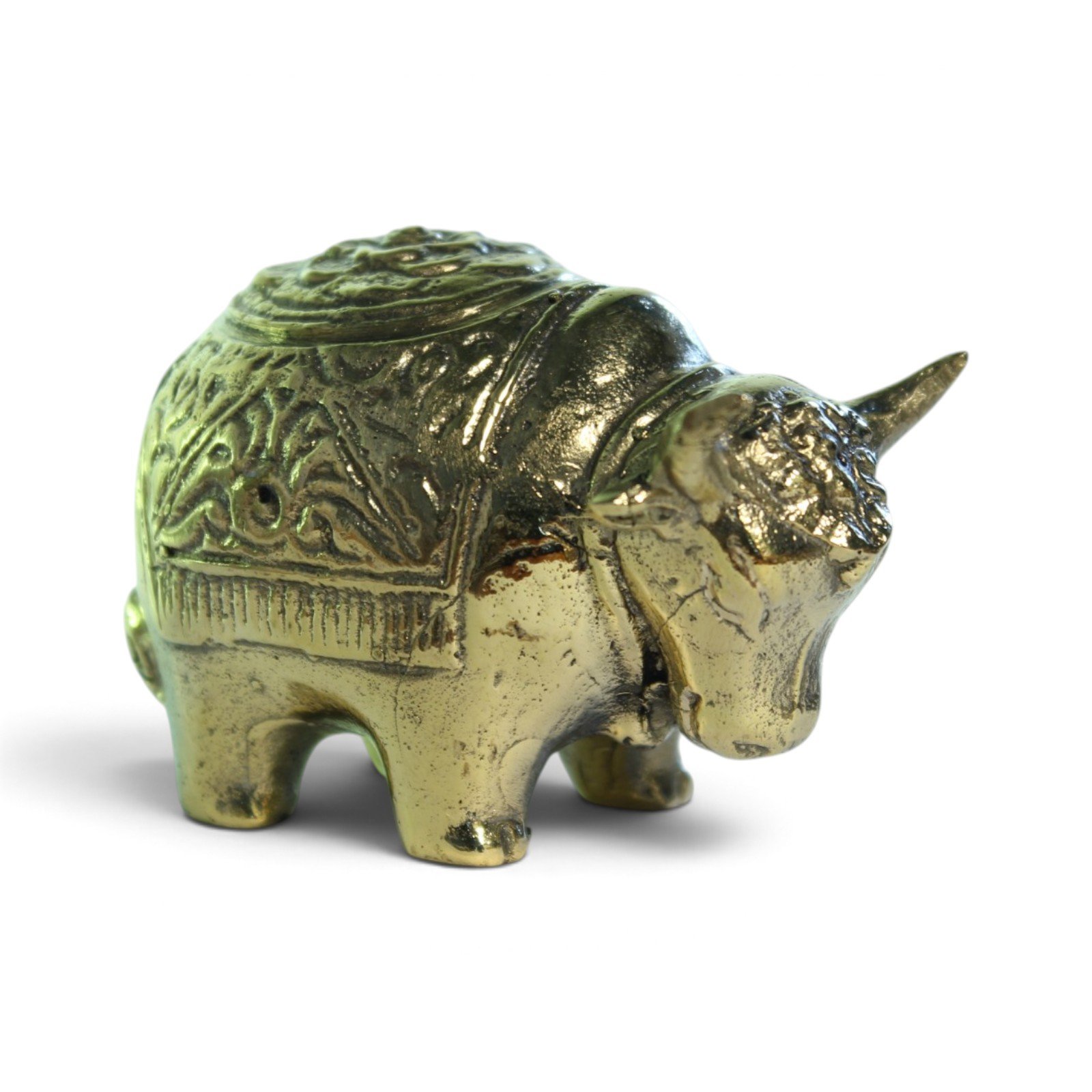 Solid brass bull figurine with patterned back, side view on white background