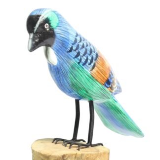 Hand-carved wooden blue bird figurine standing on a natural wood base, side view
